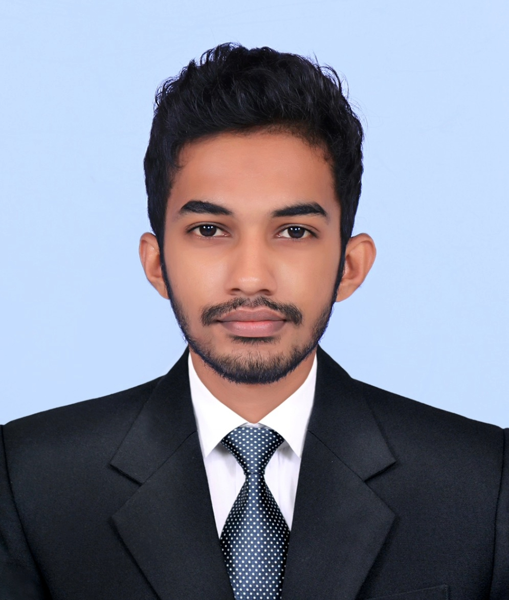 Man wearing black suit with brown hair and blue background.