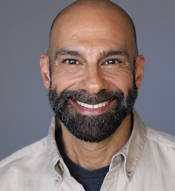 Man with beard smiling in button up shirt.